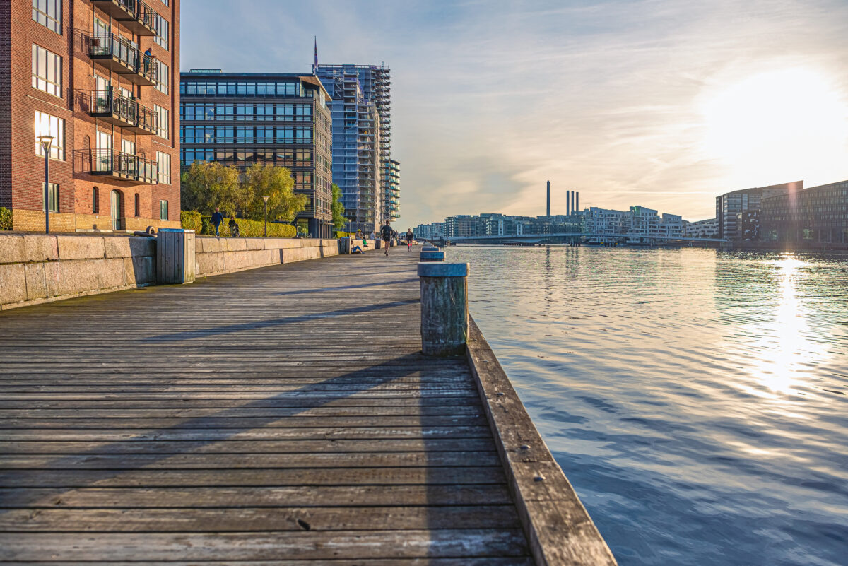 wooden embankment near the water of the canal and residential buildings at sunset. Copenhagen, Denmark